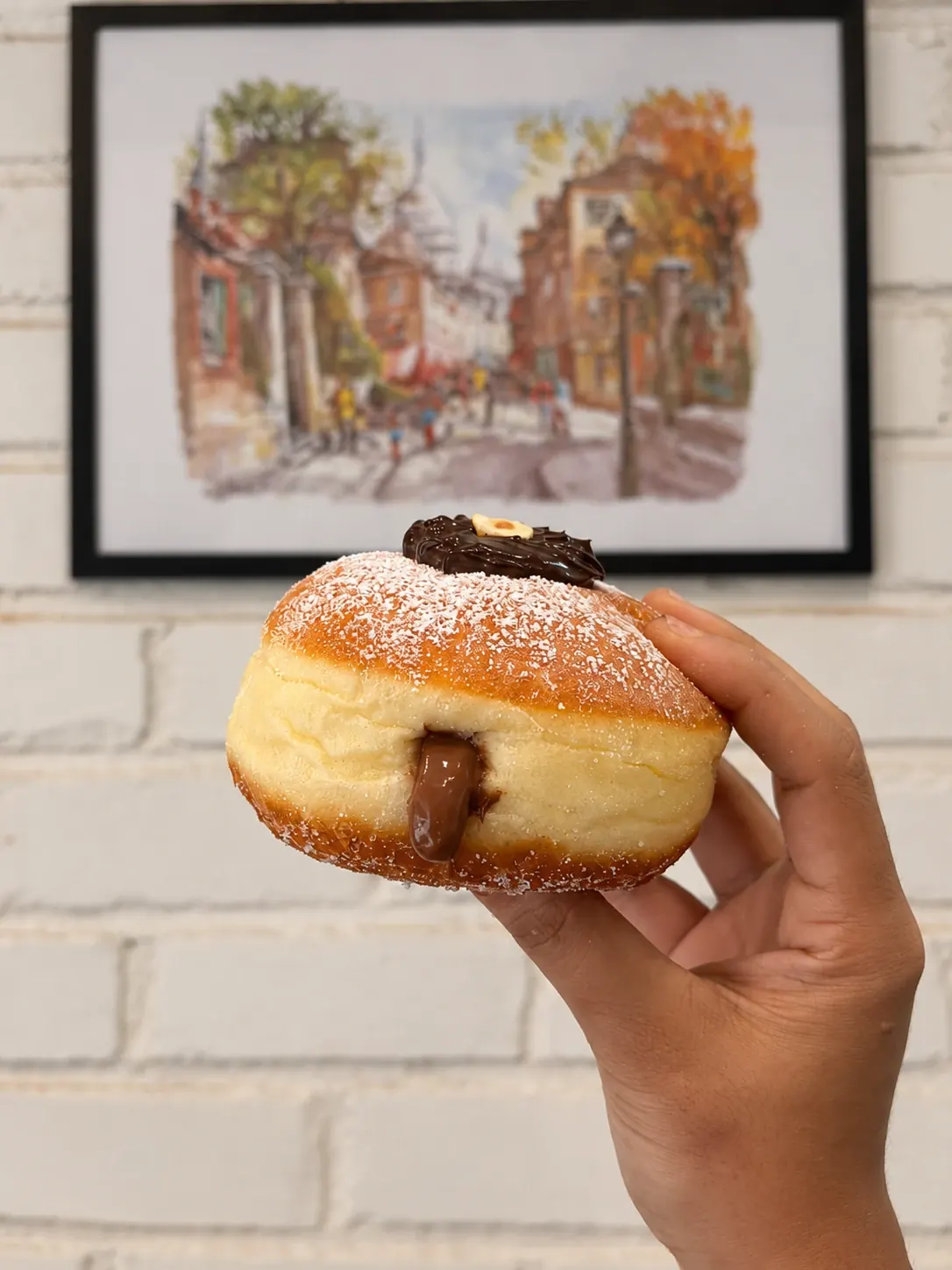 A Nutella bomboloni held up, Nutella spilling from its side, in the Minori café