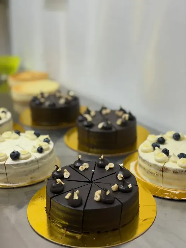 Pre-sliced chocolate hazelnut and blueberry cream cakes on gold boards in the Minori kitchen