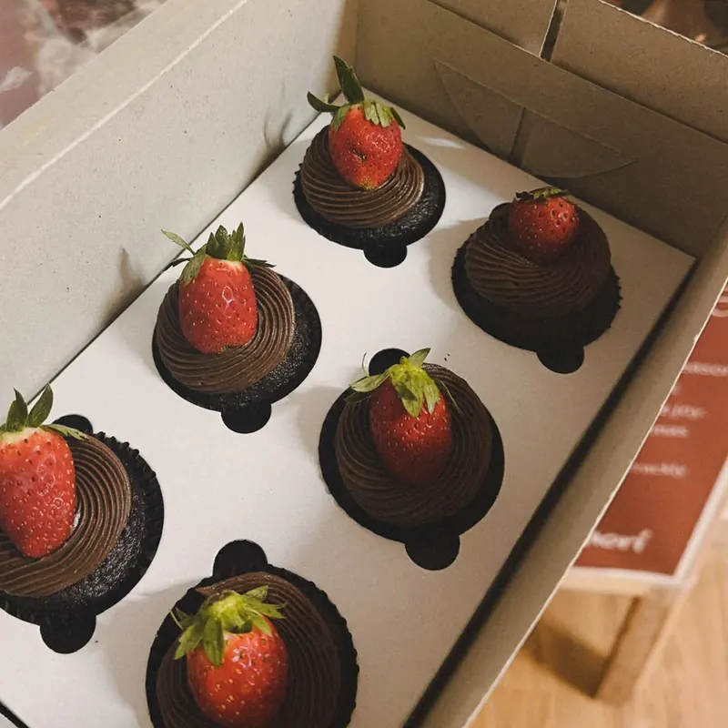 Six chocolate cupcakes with piped ganache and fresh strawberries in a Minori box