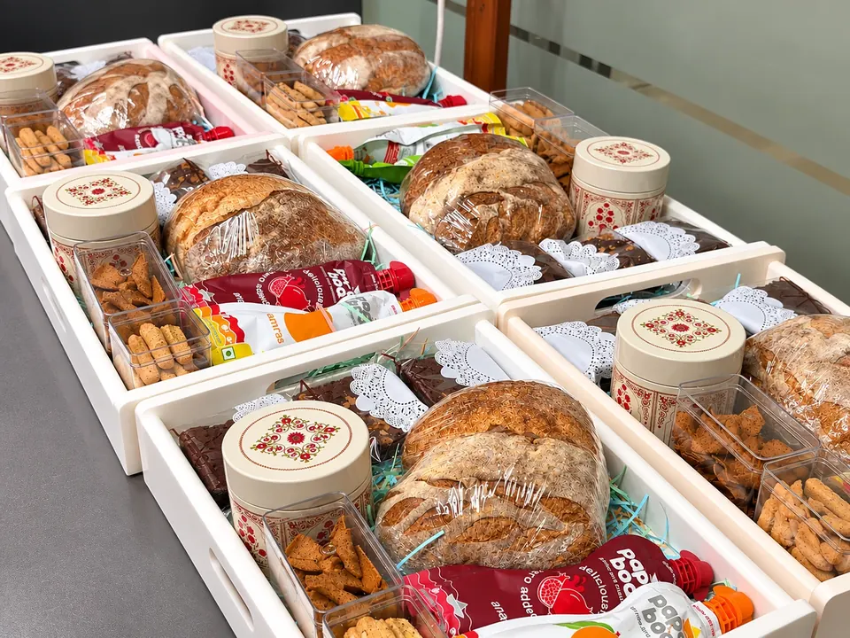 Six Minori gift trays packed for a team, each with a sourdough loaf, a patterned tin and boxes of biscotti and bakes