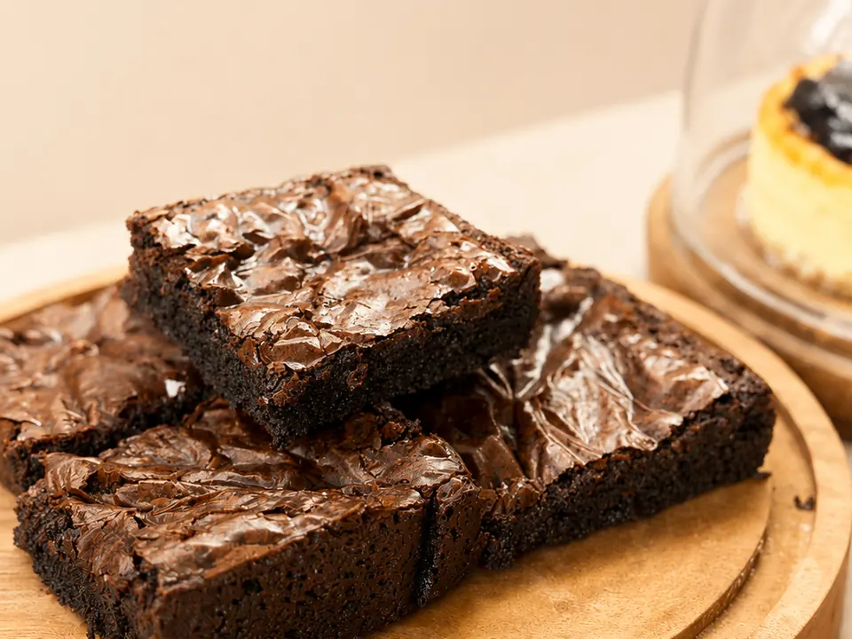 A stack of crackle-top Minori chocolate brownies on a wooden board