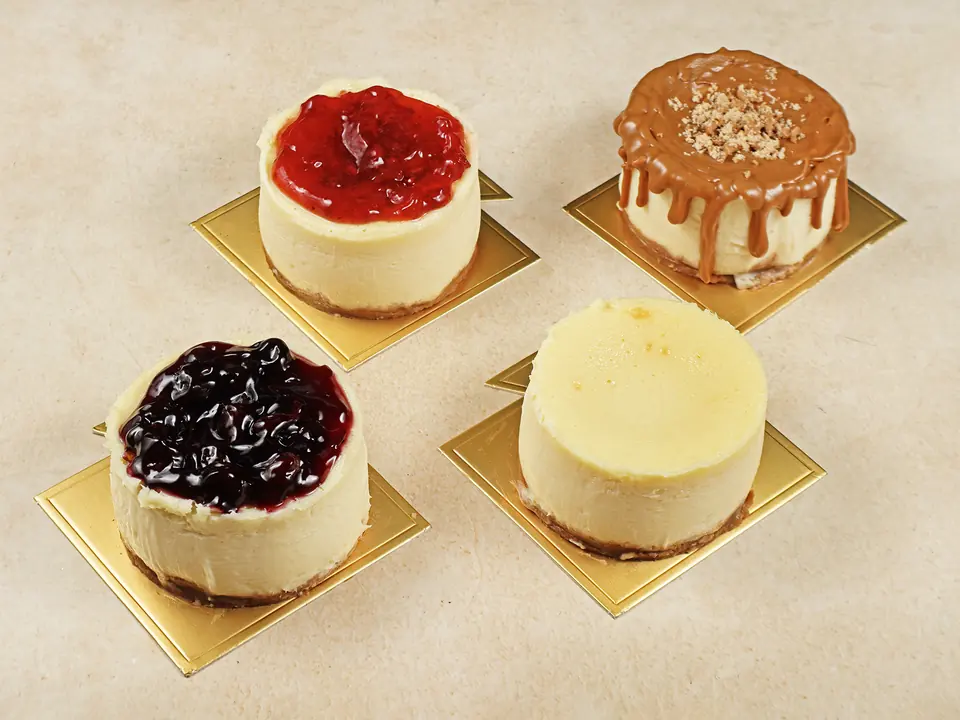 Four Minori cheesecakes on gold boards: strawberry, caramel, blueberry and New York