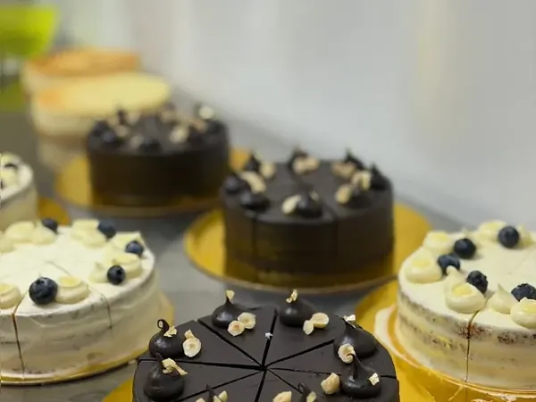 Pre-sliced chocolate hazelnut and blueberry cream cakes on gold boards in the Minori kitchen