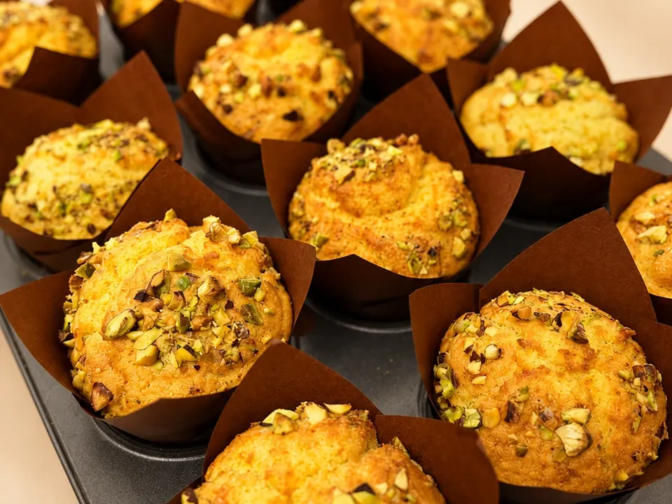 A tray of Minori kesar pista muffins in brown tulip cases